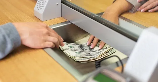 A person handing over banknotes at a counter
